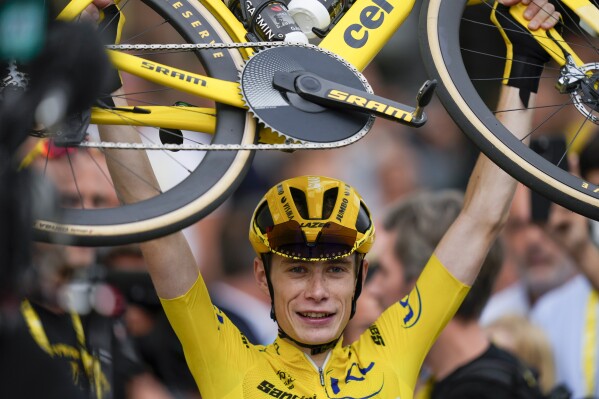 Tour de France winner Denmark's Jonas Vingegaard, wearing the overall leader's yellow jersey, lifts his bicycle after the twenty-first stage of the Tour de France cycling race over 115 kilometers (71.5 miles) with start in Saint-Quentin-en-Yvelines and finish on the Champs-Elysees avenue in Paris, France, Sunday, July 23, 2023. (AP Photo/Thibault Camus)