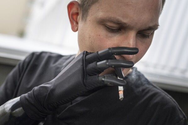 Dr. Alexis Cholas smokes a cigarette the utilization of his bionic hand exterior of the well being facility's rehabilitation center in Kyiv, Ukraine, Wednesday, Nov. 8, 2023. 
