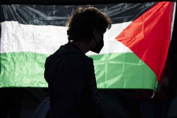 A student at the University of Oregon is silhouetted in front of a Palestinian flag inside a tent encampment at the university that was set up to protest the Israel-Hamas war, Monday, April 29, 2024, in Eugene, Ore. (AP Photo/Jenny Kane)