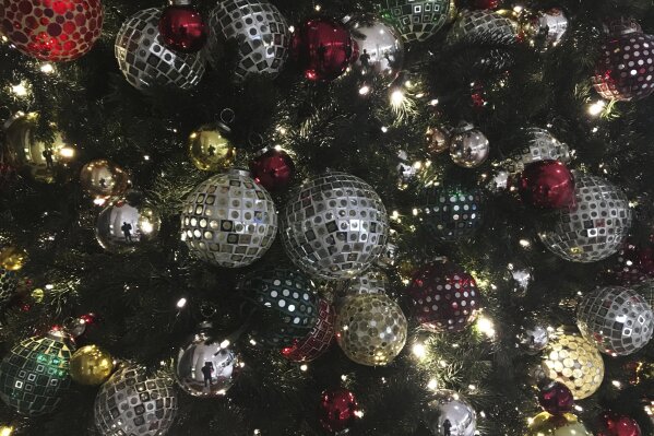 FILE - In this Friday, Dec. 1, 2017, file photo, ornaments hang on a Christmas tree on display in New York. Office holiday parties are tricky in 2020 amid the coronavirus pandemic. Dancing, drinking and fancy dinners are out. Many companies are foregoing parties altogether, deciding instead to send staff gift baskets, extra time off or donations to charities that employees choose. (AP Photo/Swayne B. Hall, File)