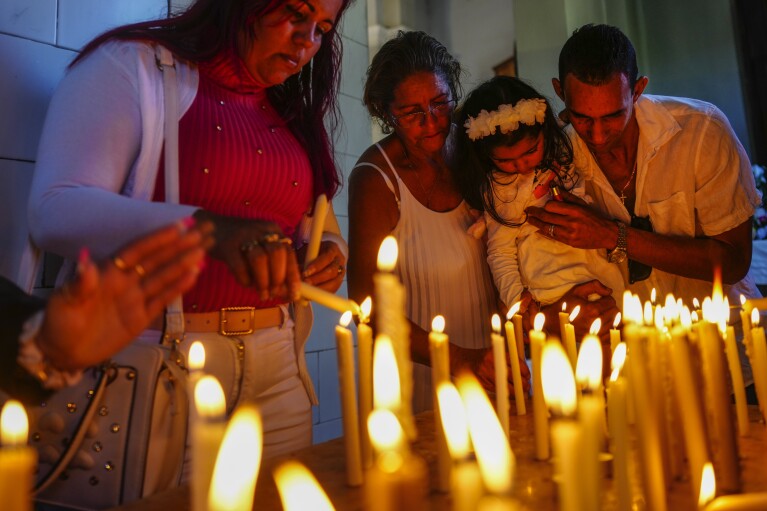 FILE - People light candles in honor of Cuba's patron saint, the Virgin of Charity of Cobre, at her shrine in El Cobre, Cuba, Feb. 11, 2024. The Vatican-recognized Virgin, venerated by Catholics and followers of Afro-Cuban Santeria traditions, is at the heart of Cuban identity. (AP Photo/Ramon Espinosa, File)