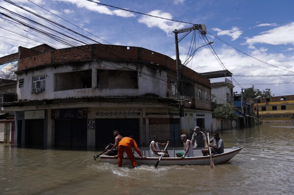 Firefighters evacuate residents through a flooded street after deadly rainfall in Belford Roxo, Brazil, Monday, Jan. 15, 2024. (AP Photo/Bruna Prado)