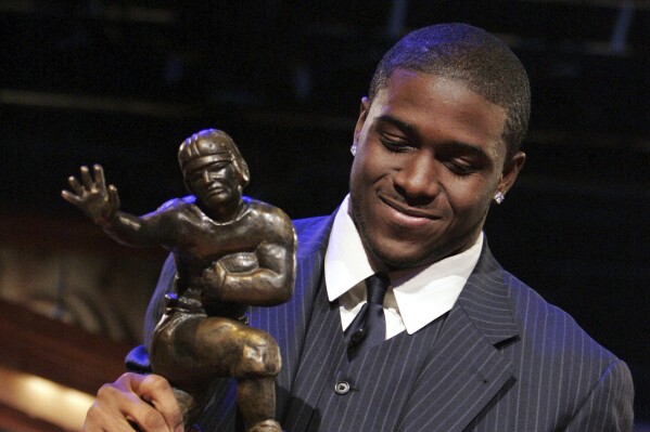 FILE - Southern California tailback Reggie Bush picks up the Heisman Trophy after being announced as the winner of the award in New York, Dec. 10, 2005. Reggie Bush has been reinstated as the 2005 Heisman Trophy winner, Wednesday, April 24, 2024, more than a decade after Southern California returned the award following an NCAA investigation that found he received what were impermissible benefits during his time with the Trojans.(AP Photo/Julie Jacobson, File)