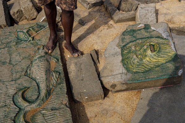 Dennis Dostey Dorve stands by a sculpture design on a collapsed wall of his late father's room, which was destroyed by coastal erosion in Avegadzi, Ghana, Wednesday, March 5, 2025 (AP Photo/Misper Apawu)