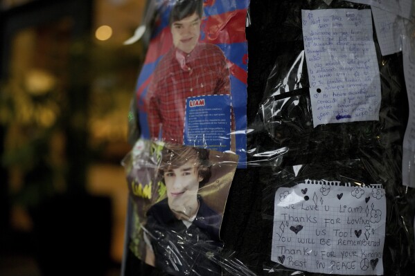 Photos of former One Direction singer Liam Payne and messages from fans are taped to a tree outside the hotel where he was found dead after falling from a balcony in Buenos Aires, Argentina, the morning after the incident, Thursday, Oct. 17, 2024. (AP Photo/Natacha Pisarenko)