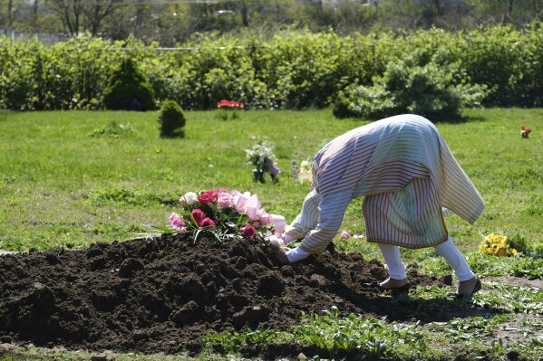 Erika Bermudez becomes emotional as she leans over the grave of her mother Eudiana Smith after she was buried in Bayview Cemetery Saturday, May 2, 2020, in Jersey City, N.J., Bermudez was not allowed to approach the gravesite until after cemetery workers had buried her mother completely; other members of the family and friends stayed in their cars. (AP Photo/Seth Wenig)