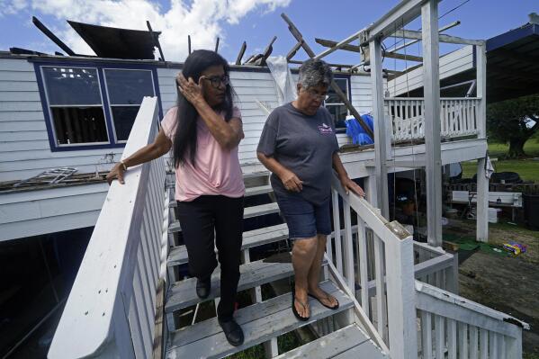 FILE - Louise Billiot, left, a member of the United Houma Nation Indian tribe, walks around the home of her friend and tribal member Irene Verdin, which was heavily damaged from Hurricane Ida nine months before, along Bayou Pointe-au-Chien, in Pointe-aux-Chenes, La., on May 26, 2022. The Federal Emergency Management Agency has developed a singular plan to engage more fully with hundreds of Native American tribes who continue to face climate change-related disasters, the agency announced Thursday, Aug. 18. (AP Photo/Gerald Herbert, File)