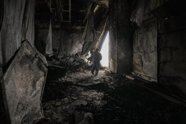 A staff member exits a large food products storage facility which was destroyed by an airstrike in the early morning hours in Brovary, north of Kyiv, Ukraine, Sunday, March 13, 2022. Waves of Russian missiles pounded a military training base close to Ukraine's western border with NATO member Poland, killing 35 people, following Russian threats to target foreign weapon shipments that are helping Ukrainian fighters defend their country against Russia's grinding invasion.(AP Photo/Vadim Ghirda)