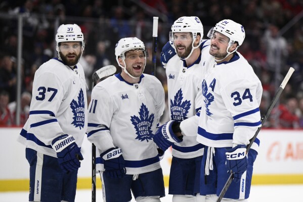 Toronto Maple Leafs center Auston Matthews (34) celebrates his goal with defenseman Timothy Liljegren (37), center Max Domi (11) and defenseman Joel Edmundson (20) during the second period of an NHL hockey game against the Washington Capitals, Wednesday, March 20, 2024, in Washington. (AP Photo/Nick Wass)