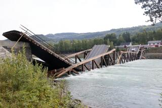 A view of a bridge that has collapsed over the River Laagen, in Gudbrandsdalen, Norway, Monday, Aug. 15, 2022.  A wooden bridge over a river in southern Norway has collapsed with a car plunging into the water and a truck getting stuck on a collapsed section. Police said the drivers of both vehicles were rescued and doing well. (Geir Olsen/NTB Scanpix via AP)