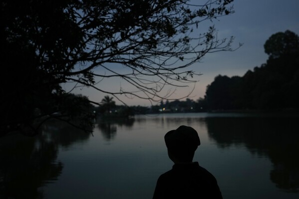 A women walks at Situ Gede lake in Bogor, West Java, Indonesia, Tuesday, Oct. 10, 2023. (AP Photo/Achmad Ibrahim)