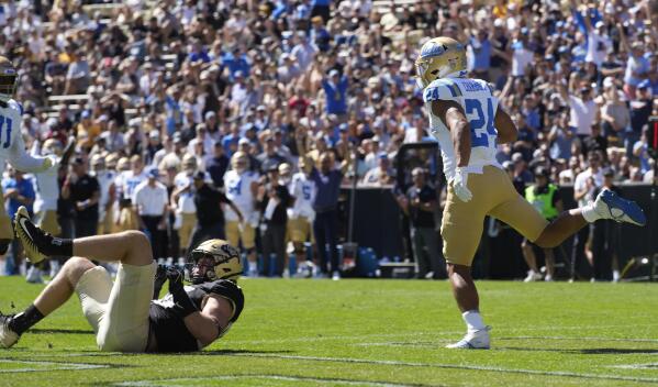 UCLA running back Zach Charbonnet, right, runs backwards into the end zone for a touchdown past Colorado defensive end Chance Main in the first half of an NCAA college football game Saturday, Sept. 24, 2022, in Boulder, Colo. (AP Photo/David Zalubowski)