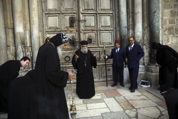 Coptic orthodox priests hold a mass outside closed Church of the Holy Sepulchre, where Christians believe Jesus Christ was buried, in Jerusalem, Saturday, March 28, 2020, as Israel tightens measures to fight the spread of the coronavirus. (AP Photo/Mahmoud Illean)