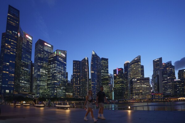 Tourists walk in front of the Central Business District during sunset in Singapore, on May 30, 2024. (AP Photo/Vincent Thian, File)