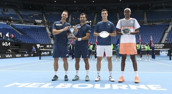 Slovakia's Filip Polasek, left, and Croatia's Ivan Dodig, second left, pose with their trophy after defeating Rajeev Ram, right, of the US and Britain's Joe Salisbury in the men's doubles final at the Australian Open tennis championship in Melbourne, Australia, Sunday, Feb. 21, 2021.(AP Photo/Andy Brownbill)