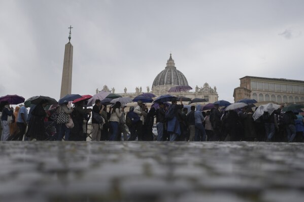 Faithful wait in line under the rain to view Pope Francis lying in state inside St. Peter's Basilica, at the Vatican,Thursday, April 24, 2025. (AP Photo/Markus Schreiber)