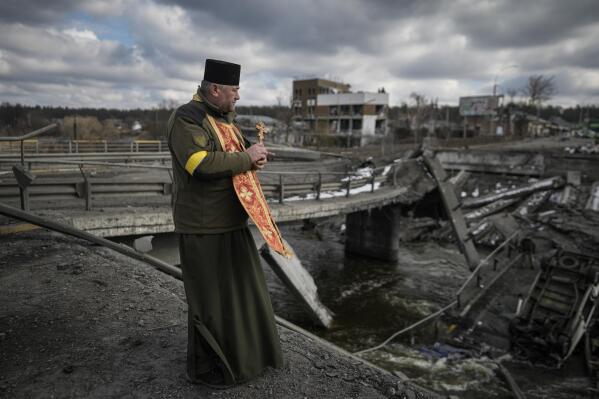 A Ukrainian military priest stands on the edge of a destroyed bridge in Irpin, on the outskirts of Kyiv, Ukraine, Wednesday, March 9, 2022. (AP Photo/Vadim Ghirda)