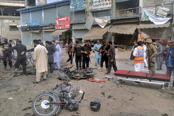 Security officials examine the site of a bomb blast in Dera Ismail Khan, Pakistan, Friday, Nov. 3, 2023. A bomb planted in a parked motorcycle exploded near a police vehicle in northwest Pakistan, killing multiple people and wounding more Friday, police said. (AP Photo/Irfan Mughal)