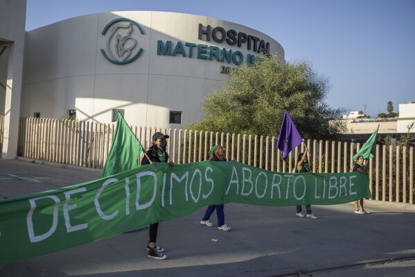 Members of the reproductive rights organization "Colectiva Bloodys y Projects" hold a banner that reads in Spanish "We decide free abortion" outside a public hospital in Tijuana, Mexico, Thursday, Sept. 28, 2023. The organization has supported reproductive rights near the U.S.-Mexico border since 2016. (AP Photo/Karen Castaneda)