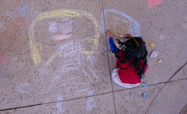A Elementary school student creates chalk art at Frye Elementary School in Chandler, Arizona Tuesday, May 23, 2023.(AP Photo/Darryl Webb)