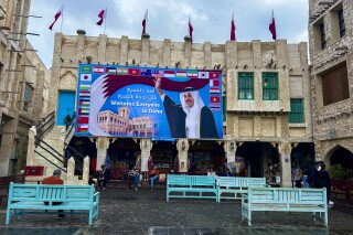A billboard with a photograph of Qatar's Amir Sheikh Tamim bin Hamad Al-Thani and the flags of several countries including India is displayed at Souk Waqif in Doha, Qatar, Sunday, Feb. 11, 2024. Qatar has freed eight retired Indian navy officers who had been given death sentences for alleged spying that were commuted last year, India's Foreign Ministry said on Monday. (APPhoto/Aijaz Rahi)
