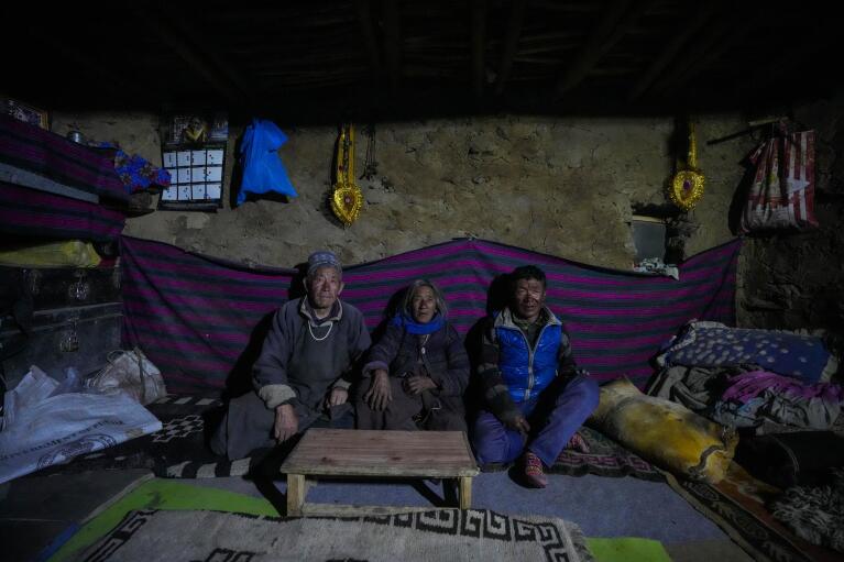 Tsering Choldan, left, with his wife Tenzin Choldan in the center pose for a picture with someone who works for them inside their mud house in remote Kharnak village in the cold desert region of Ladakh, India, Saturday, Sept. 17, 2022. As this part of Asia is particularly vulnerable to climate change, shifting weather patterns are altering people’s lives through floods, landslides and droughts in Ladakh, an inhospitable yet pristine landscape of high mountain passes and vast river valleys that in the past was an important part of the famed Silk Road trade route. (AP Photo/Mukhtar Khan)