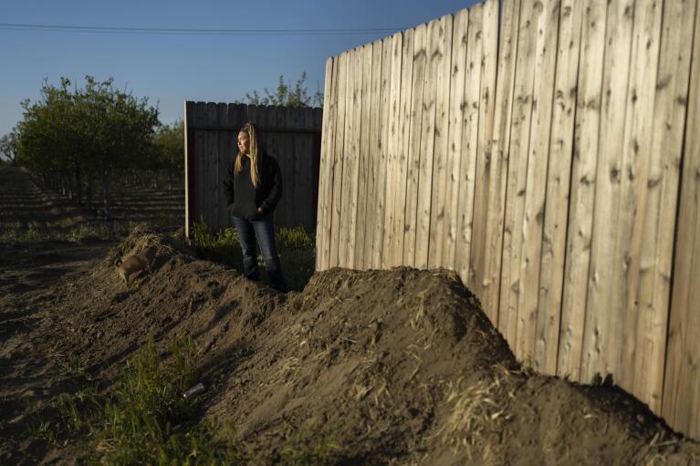 Lindzie Nail, 35, stands for a photo outside her home surrounded by a berm built in anticipation of flooding of the Kings River in the Island district of Lemoore, Calif., Thursday, April 20, 2023. After more than a dozen atmospheric rivers dumped record-setting rain and snowfall on California, residents find themselves facing the prospect of being trapped by rising rivers or flooded out. (AP Photo/Jae C. Hong)