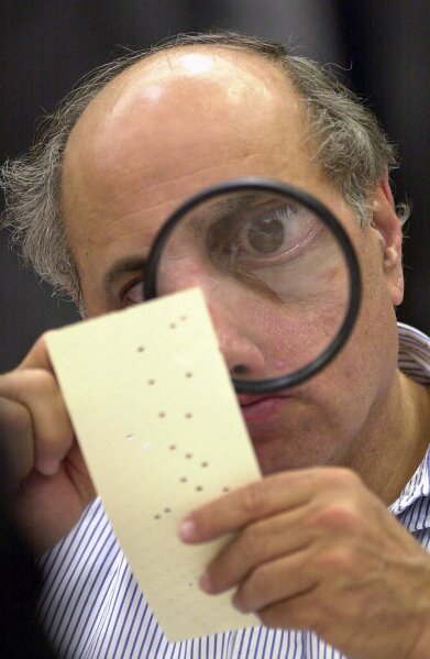 FILE - In this Nov. 24, 2000, file photo, Broward County, Fla., canvassing board member Judge Robert Rosenberg uses a magnifying glass to examine a disputed election ballot at the Broward County Courthouse in Fort Lauderdale, Fla. Two decades ago, Florida's hanging chads became an unlikely symbol of a disputed presidential election. This year, the issue could be poorly marked ovals or boxes. (AP Photo/Alan Diaz, File)