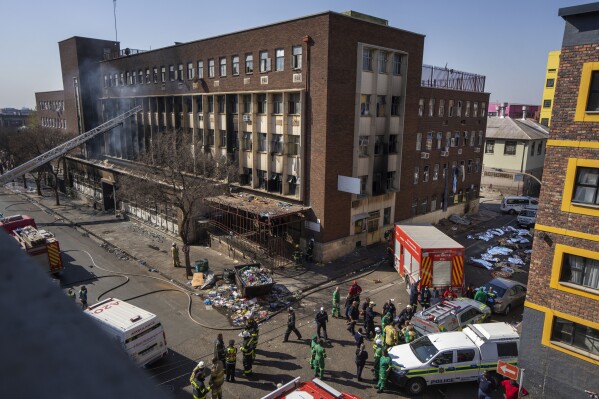 FILE - Medics stand by the covered bodies of victimes of a deadly blaze in downtown Johannesburg, South Africa, Aug. 31, 2023. The fire has reignited complaints about the continuously decaying state of the "City of Gold", as the city is affectionately known. Unhealthy finances, inward migration and crime are among some of the cited reasons for the decay. (AP Photo/Jerome Delay, File)