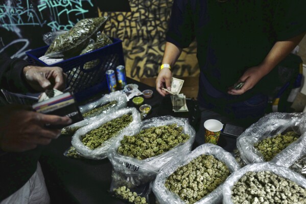 A vendor makes change for a marijuana customer at a cannabis marketplace in Los Angeles, April 15, 2019. (AP Photo/Richard Vogel, File)