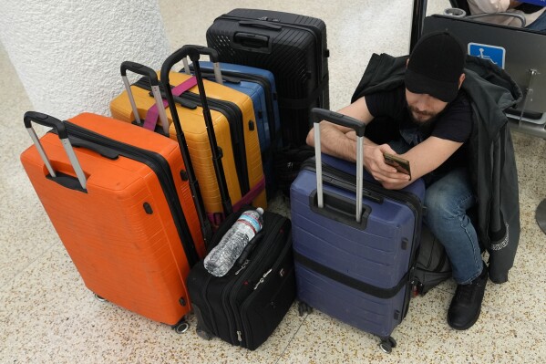 Pasha Pidlubniak waits for a domestic flight at Miami International Airport, Thursday, May 23, 2024, in Miami. A record number of Americans are expected to travel over the 2024 Memorial Day holiday. (AP Photo/Lynne Sladky)