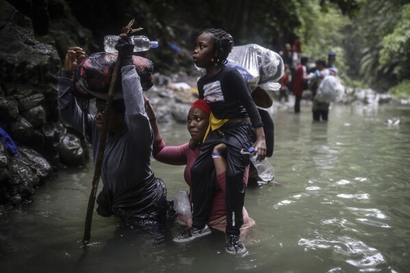 ARCHIVO - Migrantes haitianos caminan por el agua mientras cruzan el Tapón del Darién desde Colombia a Panamá con la esperanza de llegar a Estados Unidos, el 9 de mayo de 2023. (Foto AP/Iván Valencia, Archivo)