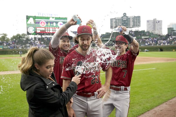 Arizona Diamondbacks' Alek Thomas, second from left, and Corbin Carroll (7) douse starting pitcher Zac Gallen (23) as sideline reporter Sara Merrifield, left, reacts after the team's win over the Chicago Cubs in a baseball game Friday, Sept. 8, 2023, in Chicago. (AP Photo/Charles Rex Arbogast)