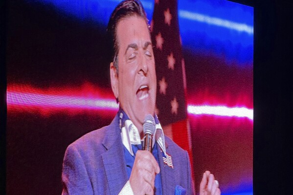 Pastor Hank Kunneman of Lord of Hosts Church in Omaha, Nebraska, is projected on a large screen as he speaks at the Opening the Heavens conference on Friday, Sept. 13, 2024, at the Mid-America Center in Council Bluffs, Iowa. (AP Photo/Peter Smith)