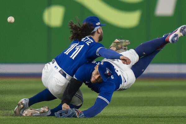 Toronto Blue Jays shortstop Bo Bichette (11) and Toronto Blue Jays center fielder George Springer collide while trying to catch a short fly ball during the eighth inning of Game 2 of a baseball AL wild-card playoff series Saturday, Oct. 8, 2022, in Toronto. (Frank Gunn/The Canadian Press via AP)