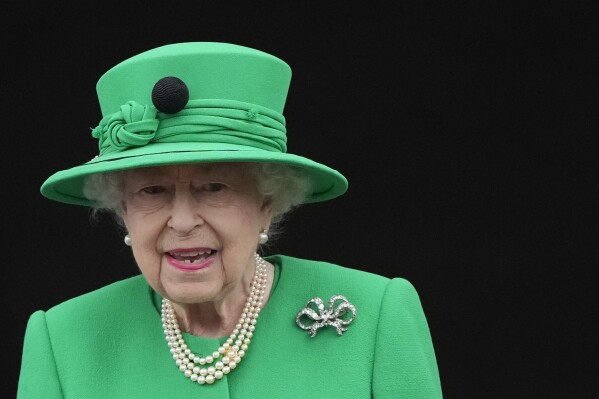 FILE - Queen Elizabeth II stands on the balcony during the Platinum Jubilee Pageant at the Buckingham Palace in London, Sunday, June 5, 2022, on the last of four days of celebrations to mark the Platinum Jubilee. A 26-year-old man has been sentenced on Monday Jan. 8, 2024 for defrauding eBay buyers by trying to sell what he claimed was a walking stick used by the late Queen Elizabeth II as she struggled with mobility in old age. (AP Photo/Frank Augstein, Pool, File)