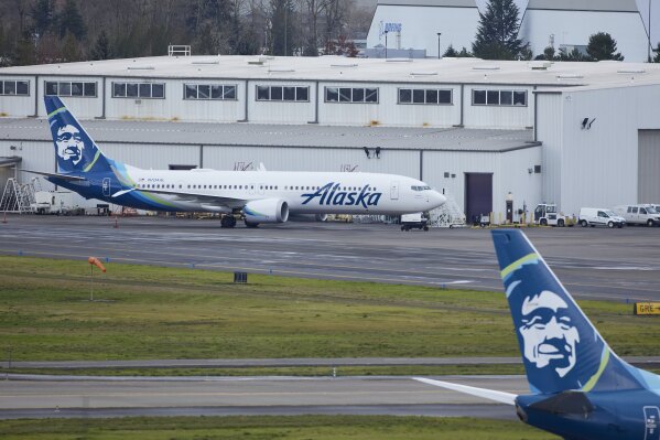 Alaska Airlines N704AL, a 737 Max 9 which made an emergency landing at Portland International Airport after a part of the fuselage broke off mid-flight on Friday, is parked at a maintenance hanger in Portland, Ore., Saturday, Jan. 6, 2024. (AP Photo/Craig Mitchelldyer)