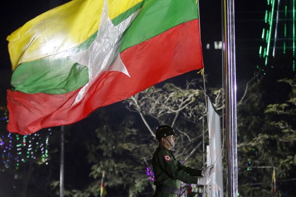 FILE - A Myanmar military soldier hoists a national flag during a ceremony to mark the 69th anniversary of Independence Day in Yangon, Myanmar on Jan. 4, 2017. A Swiss citizen was arrested in military-ruled Myanmar for writing a screenplay and creating a film that allegedly insulted Buddhism, state media reported Saturday, Aug. 19, 2023. (AP Photo, File)