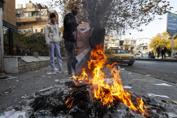 A Syrian man burns a picture of ousted Syrian President Bashar Assad in Damascus, Syria, Monday, Dec. 9, 2024. (AP Photo/Omar Sanadiki)