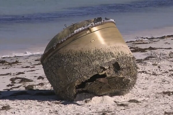 In this image made from video, a cylindrical object is seen on beach in Green Head, Australia, July 17, 2023. Authorities were investigating on Tuesday whether a cylindrical object about the size of a small car that washed up on a remote Australian beach is space junk from a foreign rocket. (CHANNEL 9 via AP)