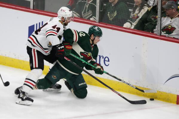 Minnesota Wild left wing Kevin Fiala (22) and Chicago Blackhawks defenseman Calvin de Haan (44) vie for the puck in the first period of an NHL hockey game Saturday, March 19, 2022, in St. Paul, Minn. (AP Photo/Andy Clayton-King)