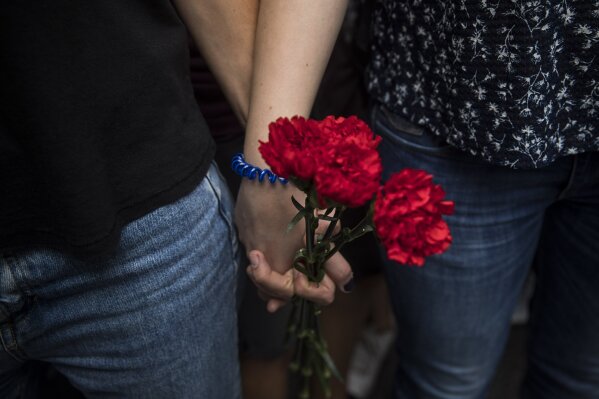 
              Two people hold hands with flowers during a one-day strike protest in Barcelona, Spain, Tuesday Oct. 3, 2017. Labor unions and grassroots pro-independence groups are urging workers to hold partial or full-day strikes throughout Catalonia to protest alleged brutality by police during a referendum on the region's secession from Spain that left hundreds of people injured. (AP Photo/Santi Palacios)
            