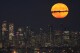 FILE - A supermoon rises through clouds over the skyline of lower Manhattan, Aug. 1, 2023, as seen from West Orange, N.J. Stargazers are in for a double treat on Wednesday night, Aug. 30: a rare blue supermoon with Saturn peeking from behind. The cosmic curtain rises Wednesday night with the second full moon of August, the reason it’s considered blue. It’s dubbed a supermoon because it’s closer to Earth than usual, appearing especially big and bright. (AP Photo/Seth Wenig, File)