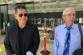 FILE - Stewart Olani Stant, left, listens while his attorney Cary Virtue speaks to reporters outside U.S. District Court in Honolulu on Sept. 19, 2022. Stant, who was formerly a wastewater manager and the director of Maui's Department of Environmental Management, was sentenced Wednesday, Feb. 8, 2023, to 10 years in prison for accepting $2 million in bribes from a Honolulu businessman in one of the biggest bribery cases in Hawaii history. (AP Photo/Audrey McAvoy, File)