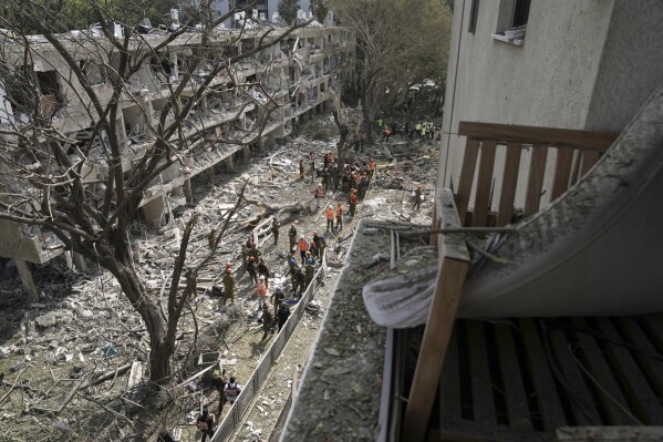 Israel's home front command officers and rescue workers survey the site of a direct missile strike launched from Iran in Tel Aviv, Israel, Sunday, June 22, 2025. (AP Photo/Oded Balilty)