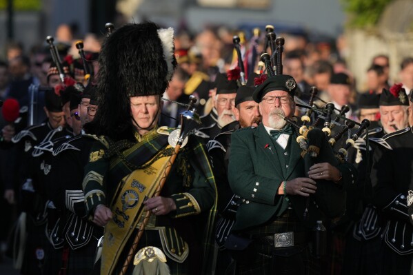 A pipe band makes the procession from Bayeux Cathedral to the military cemetery walking in front of Britain's Princess Anne and other dignitaries to take part in a vigil in memory of the fallen during the D-Day invasion in 1944, in Bayeux, Normandy, France, Wednesday, June 5, 2024. (AP Photo/Alastair Grant)