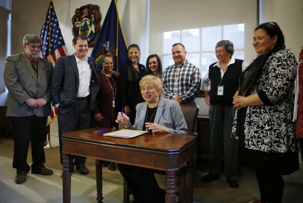 FILE - In this April 26, 2019, file photo, Maine Gov. Janet Mills signs a bill to establish Indigenous Peoples' Day at the State House in Augusta, Maine. A handful of states, including New Mexico and Maine, are celebrating their first Indigenous Peoples' Day as part of a trend to move away from a day honoring Christopher Columbus. (AP Photo/Robert F. Bukaty, File)