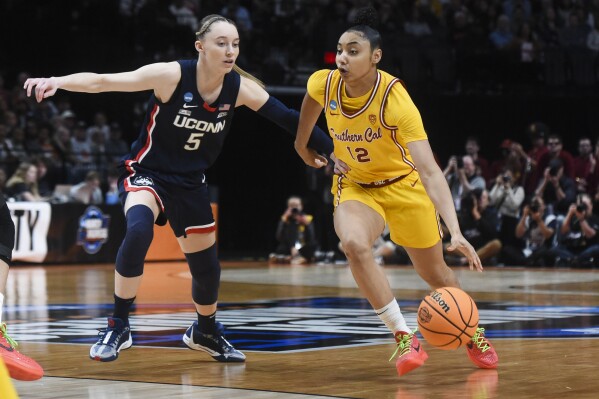 FILE - Southern California guard JuJu Watkins (12) drives to the basket past UConn guard Paige Bueckers (5) during the first half of an Elite Eight college basketball game in the women's NCAA Tournament, April 1, 2024, in Portland, Ore. Southern California and UConn have agreed to a home-and-home series, which will have stars Watkins and Bueckers facing off against each other in December. (AP Photo/Steve Dykes, File)