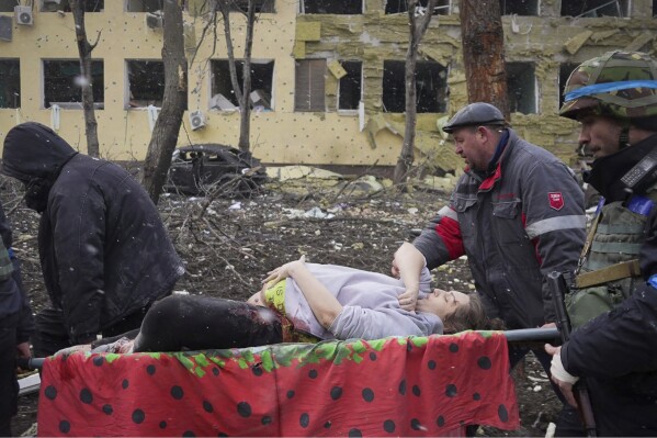 FILE - Ukrainian emergency workers and volunteers carry an injured pregnant woman from a maternity hospital damaged by an airstrike in Mariupol, Ukraine, on March 9, 2022. The image is part of the documentary film 