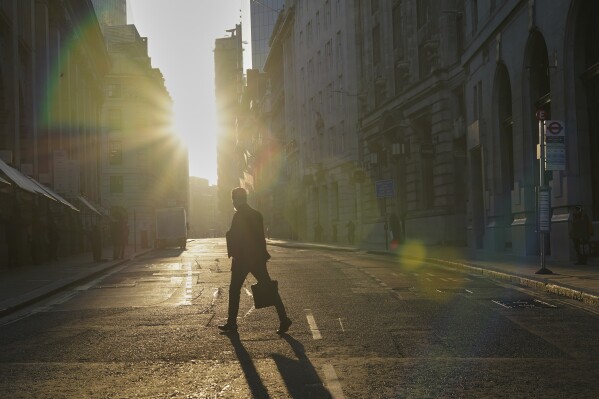 A man walks in the the City of London financial district, London, Tuesday, April 8, 2025. (AP Photo/Alberto Pezzali)